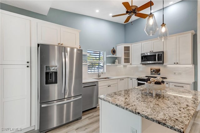 kitchen with stainless steel appliances, white cabinetry, sink, and light stone counters