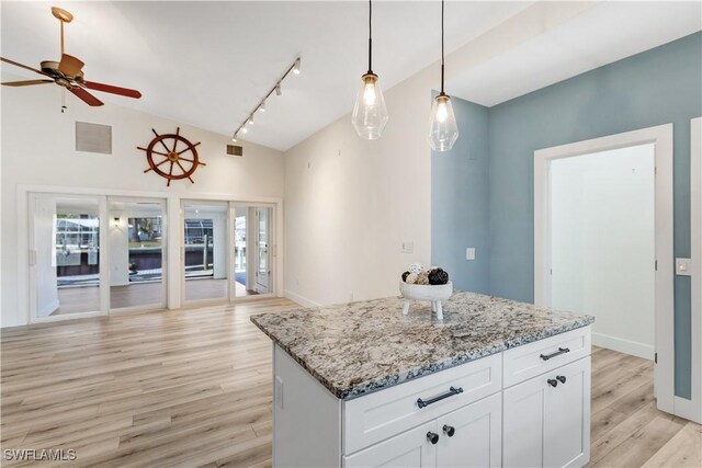 kitchen featuring light hardwood / wood-style flooring, white cabinetry, hanging light fixtures, light stone countertops, and a kitchen island