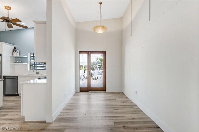 foyer featuring french doors, sink, light wood-type flooring, and a towering ceiling