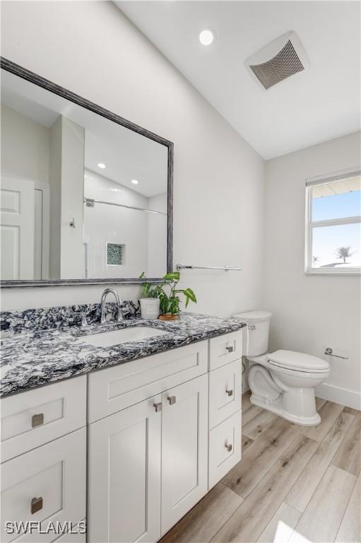 bathroom with vanity, a shower, hardwood / wood-style floors, and toilet