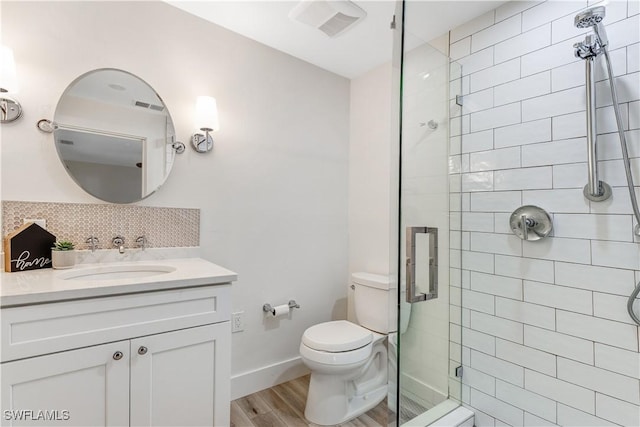 bathroom with hardwood / wood-style floors, vanity, decorative backsplash, a shower with shower door, and toilet