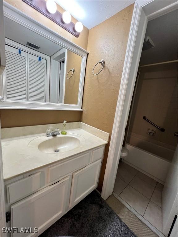 bathroom featuring a textured wall, tile patterned flooring, and vanity