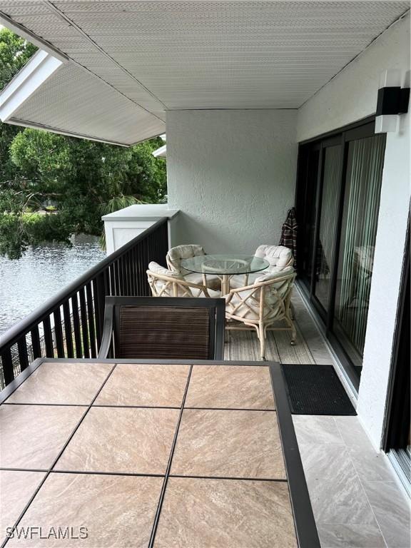 balcony with outdoor dining area and a water view