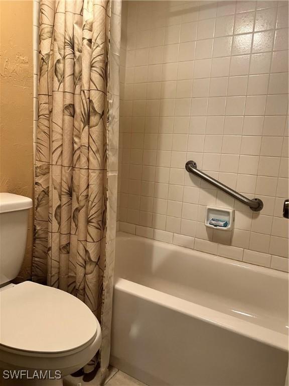 full bathroom featuring a textured wall, shower / bathtub combination with curtain, and toilet