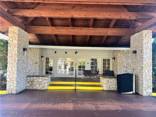 view of exterior entry with stone siding, french doors, and a patio area