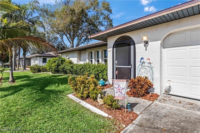 view of exterior entry with a garage and a lawn