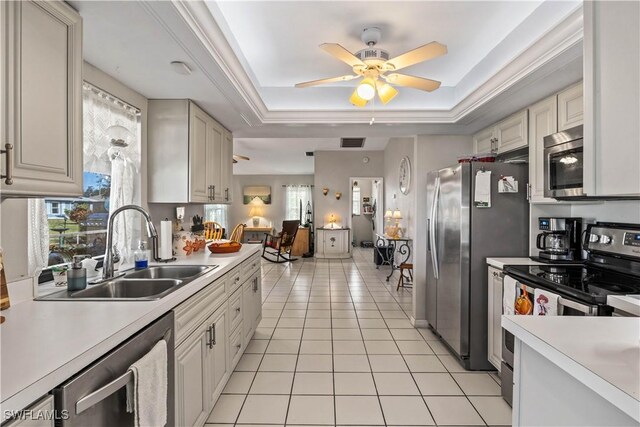 kitchen with sink, light tile patterned floors, ceiling fan, stainless steel appliances, and a raised ceiling