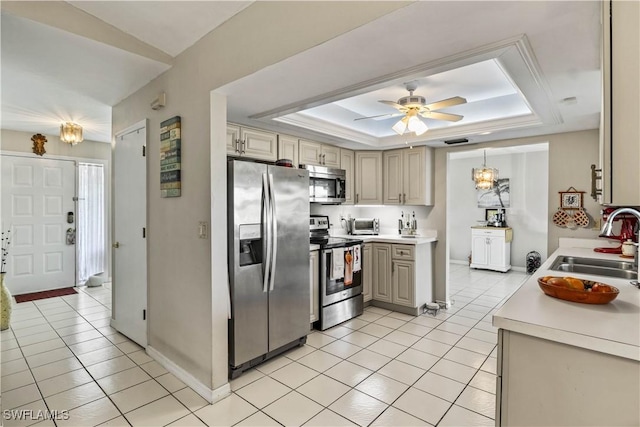 kitchen with light tile patterned flooring, appliances with stainless steel finishes, a tray ceiling, and sink