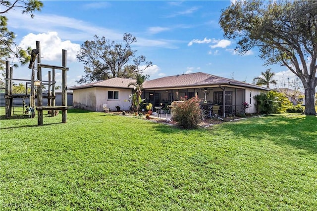 rear view of property with a sunroom, a yard, and stucco siding