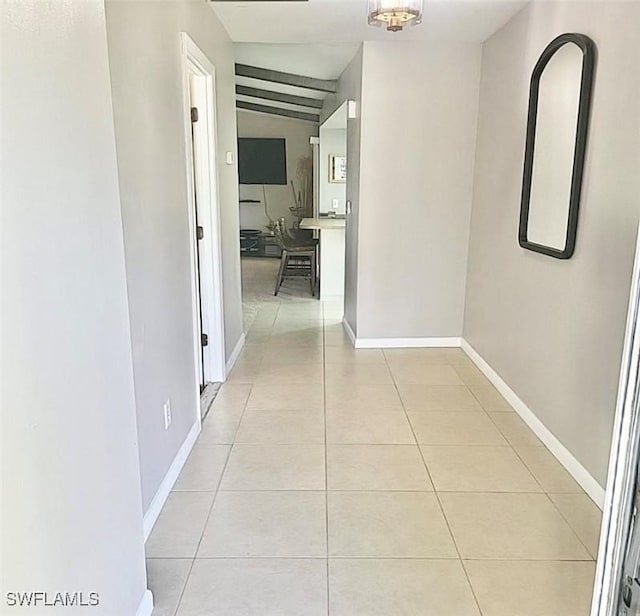 corridor featuring light tile patterned flooring and baseboards