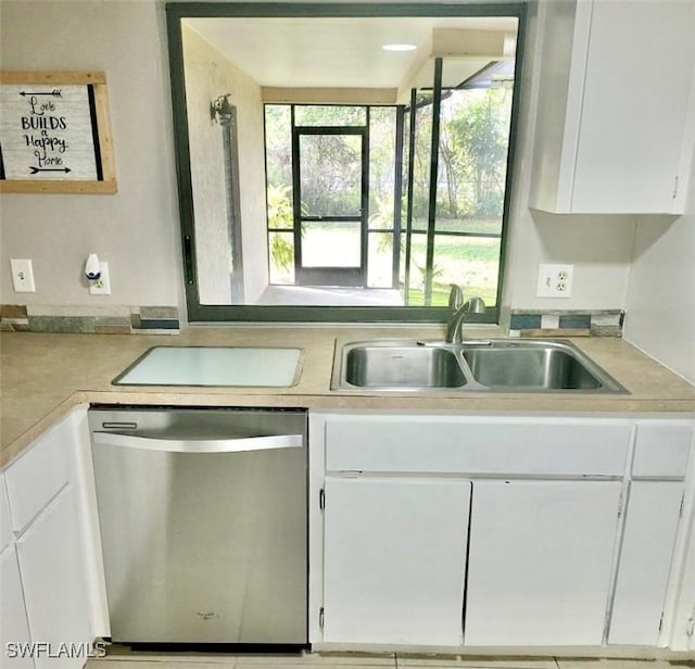 kitchen featuring light countertops, stainless steel dishwasher, a sink, and white cabinets