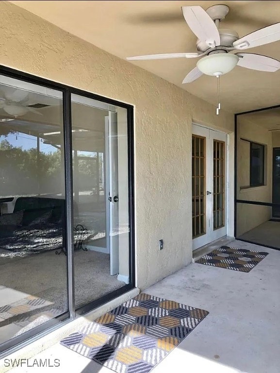 property entrance featuring stucco siding, ceiling fan, and french doors