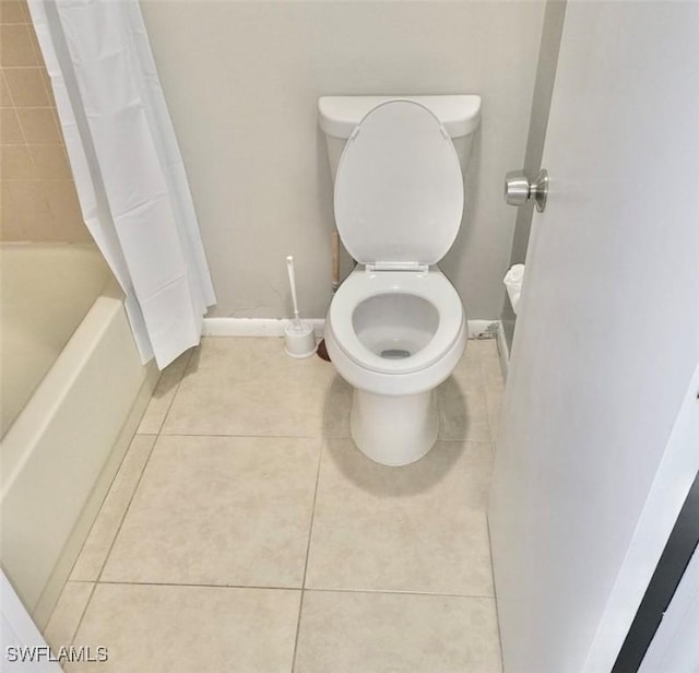 bathroom with toilet, baseboards, and tile patterned floors