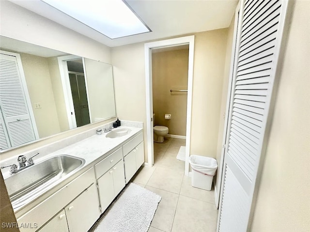 full bathroom with a closet, a sink, toilet, and tile patterned floors