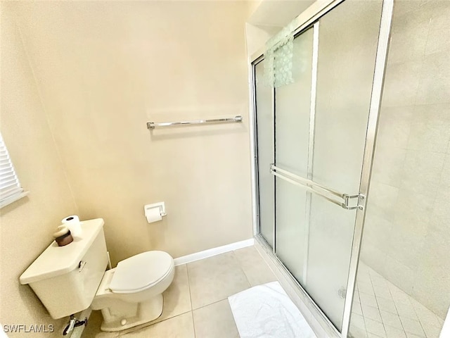 bathroom with toilet, a stall shower, baseboards, and tile patterned floors