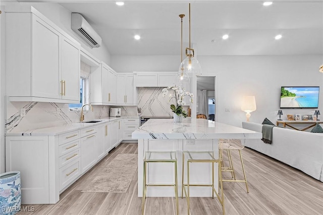 kitchen featuring backsplash, a center island, light stone counters, a wall mounted air conditioner, and white cabinets