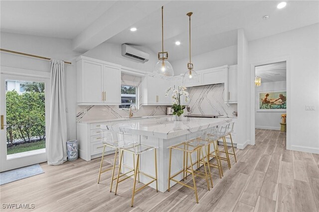 kitchen featuring a wall mounted air conditioner, a center island, light hardwood / wood-style floors, decorative backsplash, and white cabinets