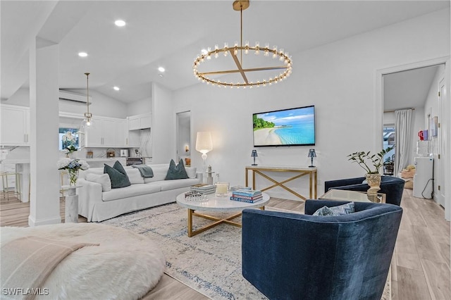 living room with vaulted ceiling, a notable chandelier, and light wood-type flooring