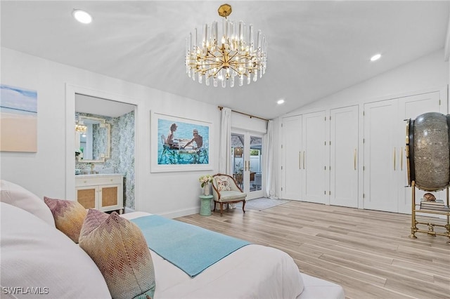 bedroom with ensuite bathroom, two closets, lofted ceiling, a notable chandelier, and light hardwood / wood-style floors