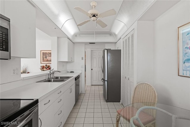 kitchen featuring a sink, white cabinets, light countertops, appliances with stainless steel finishes, and a tray ceiling