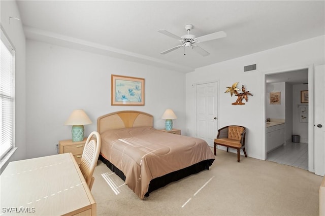 bedroom featuring visible vents, ceiling fan, light carpet, and ensuite bath