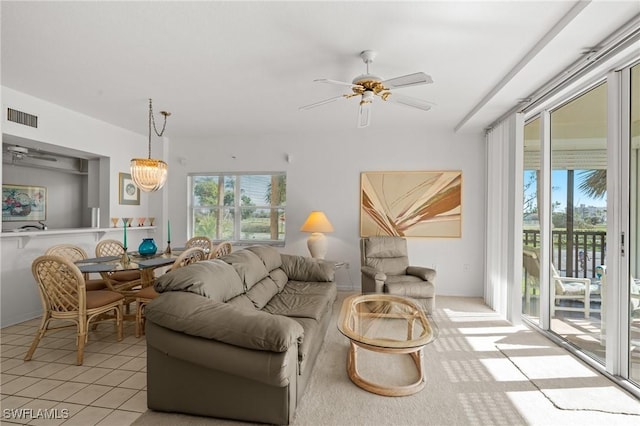 living room with light tile patterned flooring, a healthy amount of sunlight, visible vents, and ceiling fan with notable chandelier