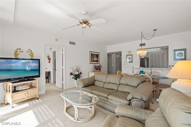 living area featuring ceiling fan with notable chandelier, visible vents, and light colored carpet