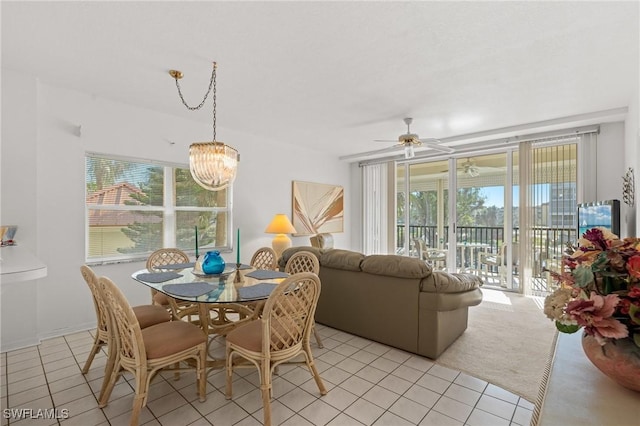 dining area featuring ceiling fan with notable chandelier, light tile patterned flooring, and light colored carpet