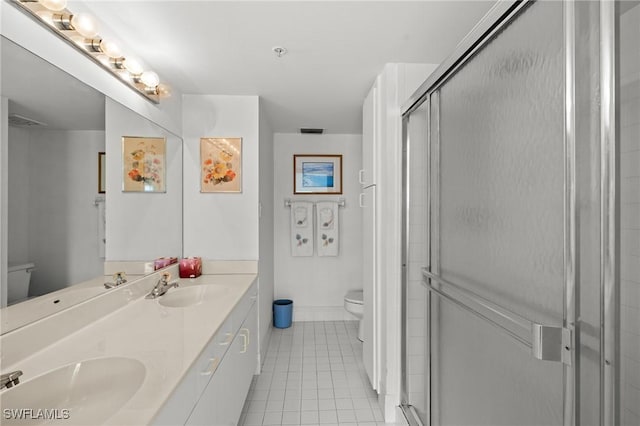 bathroom with a stall shower, a sink, toilet, and tile patterned floors