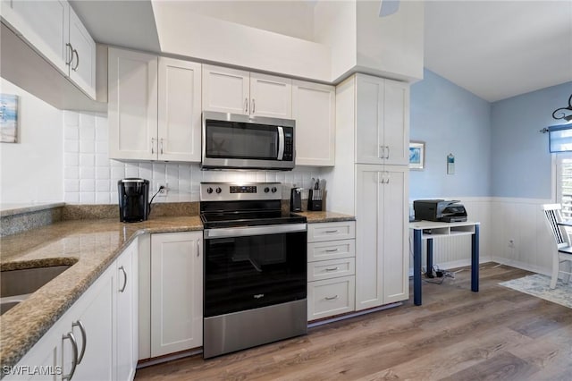 kitchen with light hardwood / wood-style flooring, light stone countertops, white cabinets, and appliances with stainless steel finishes