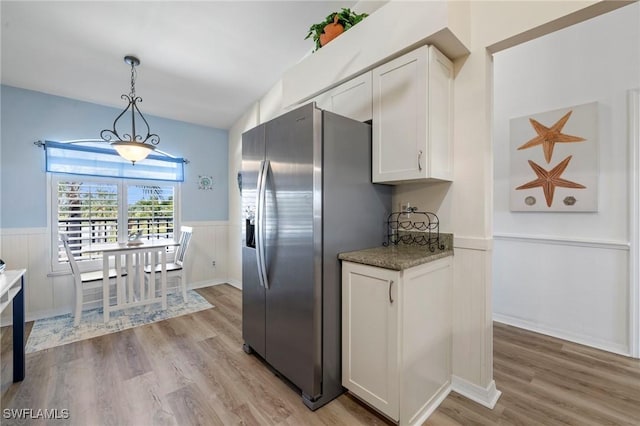 kitchen with white cabinetry, stainless steel refrigerator with ice dispenser, light hardwood / wood-style flooring, and decorative light fixtures