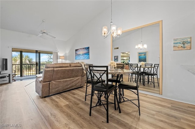 dining area with high vaulted ceiling, ceiling fan with notable chandelier, and light hardwood / wood-style floors