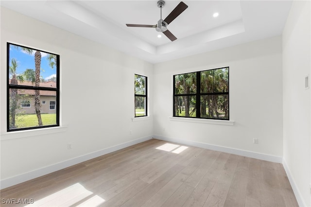 unfurnished room featuring ceiling fan, light hardwood / wood-style floors, and a tray ceiling