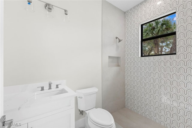 bathroom featuring vanity, toilet, and a tile shower