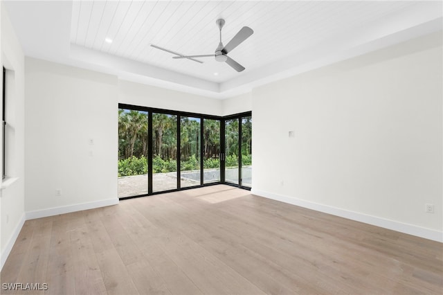 unfurnished room with light hardwood / wood-style flooring, wood ceiling, ceiling fan, and a tray ceiling