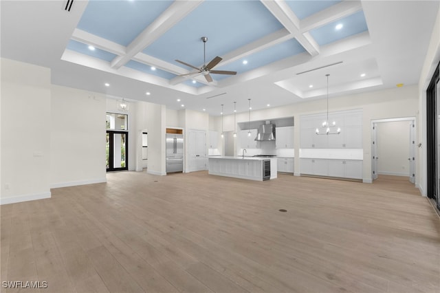 unfurnished living room with coffered ceiling, ceiling fan with notable chandelier, and light wood-type flooring