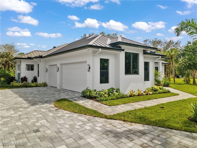 740 13th St NW, Naples, FL 34120 - view of side of home with a standing seam roof, a garage, decorative driveway, and stucco siding