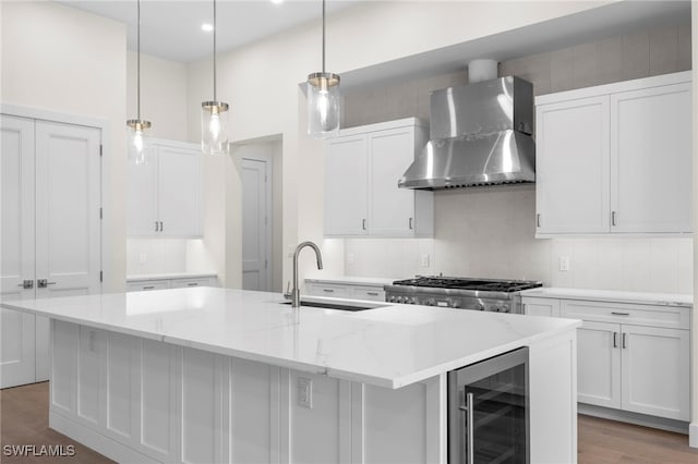 740 13th St NW, Naples, FL 34120 - kitchen with wall chimney range hood, wine cooler, wood finished floors, an island with sink, and backsplash
