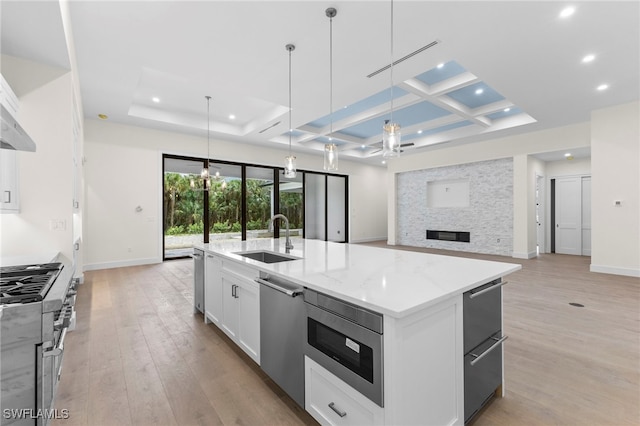 kitchen featuring pendant lighting, sink, a kitchen island with sink, stainless steel appliances, and white cabinets