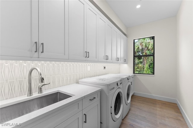 laundry room with cabinets, washer and clothes dryer, sink, and light wood-type flooring