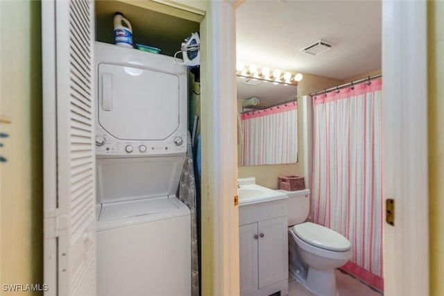 bathroom featuring toilet, vanity, and stacked washing maching and dryer