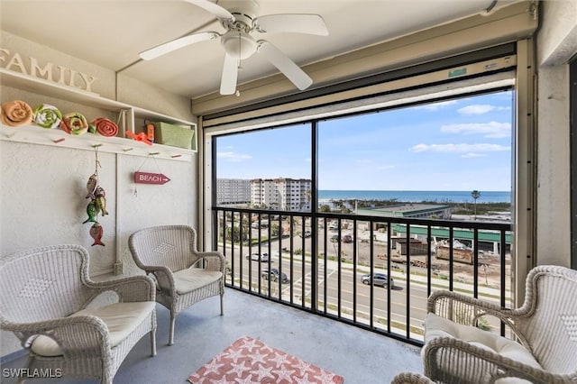 sunroom featuring a water view and ceiling fan