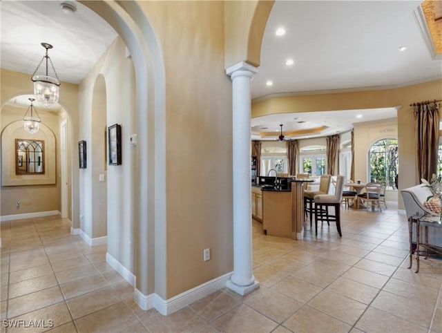 corridor with light tile patterned flooring, ornamental molding, sink, and ornate columns