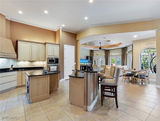 kitchen with stainless steel microwave, sink, black oven, and a center island with sink