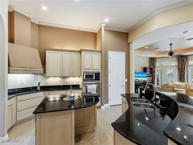 kitchen featuring sink, crown molding, light tile patterned floors, an island with sink, and decorative backsplash