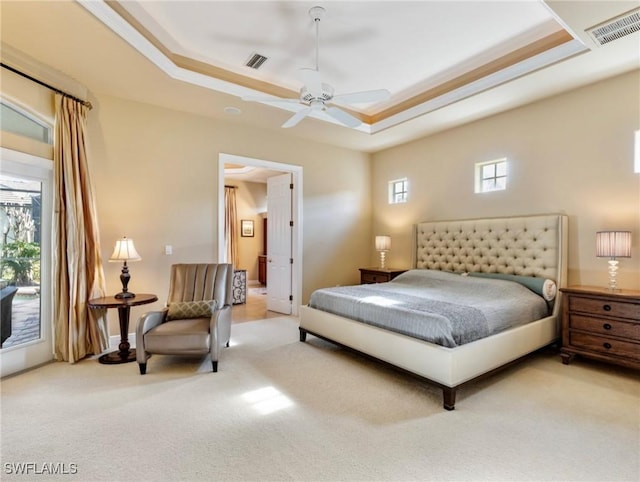 carpeted bedroom featuring ceiling fan and a tray ceiling