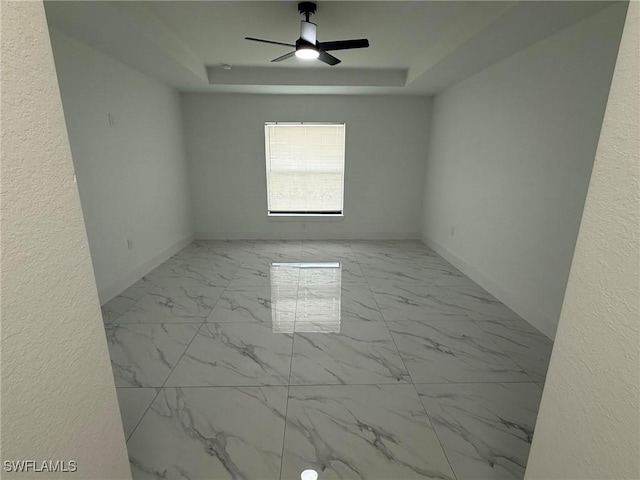 unfurnished room featuring ceiling fan and a tray ceiling