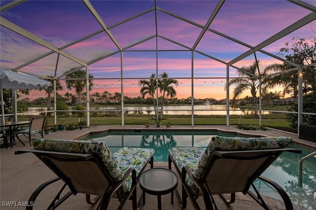 pool at dusk featuring a water view, a patio area, and glass enclosure