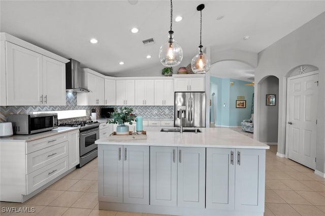 kitchen featuring an island with sink, appliances with stainless steel finishes, white cabinets, and wall chimney exhaust hood