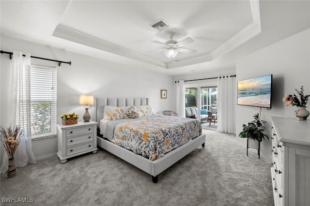 carpeted bedroom with access to exterior, a tray ceiling, and ornamental molding